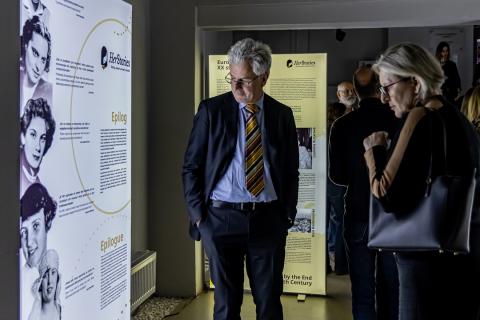 Gallery at the Museum with the exhibition HerStories. Consuls of Austria and Slovakia visiting the exhibition, standing in front of an exhibition panel containing black and white portraits of seven women and short texts.